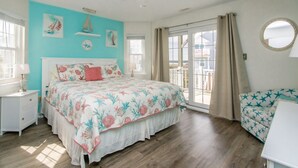 A bedroom with a bed, a nightstand, a dresser, a ceiling fan, and a view of the outside.