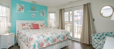 A bedroom with a bed, a nightstand, a dresser, a ceiling fan, and a view of the outside.
