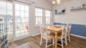 A dining area with a wooden table and white chairs, a sliding glass door leading to a balcony, and a blue accent wall with decorative items.