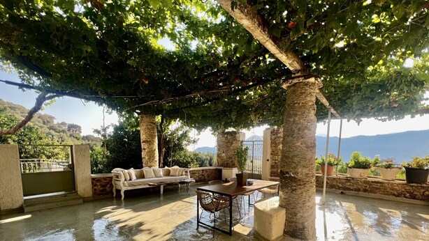 An outdoor patio with stone pillars, a sofa, and a table. - The Stone House (Kakodiki)