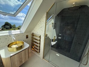 A modern bathroom with a skylight, a glass-enclosed shower, and a freestanding bathtub.