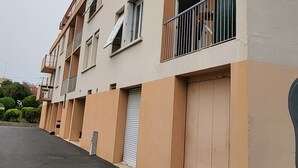 En flervåningsbyggnad med bostäder, balkonger, en garageport och en asfalterad uppfart.
