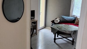 Ett rum med en säng, en stol, ett litet bord och en spegel på väggen.
