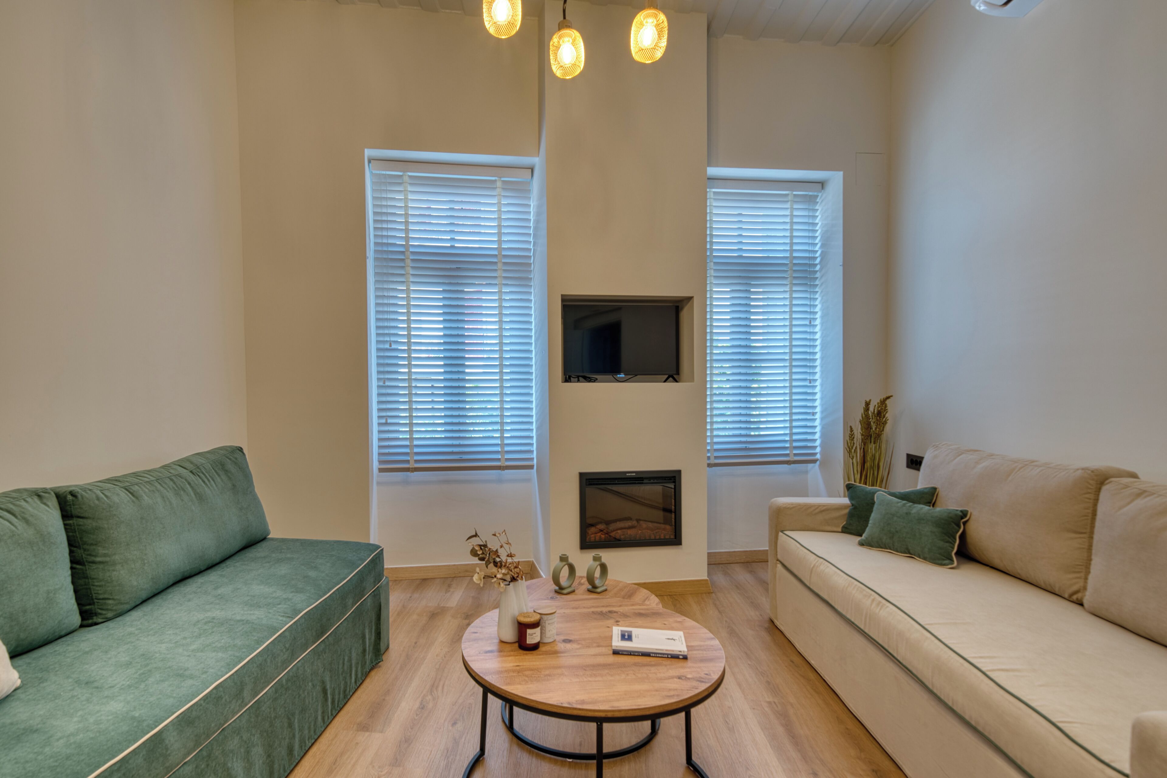 A living room with a green sofa, a beige sofa, a wooden coffee table, and a fireplace.