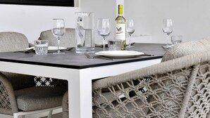 A dining table set with wine glasses, a pitcher, and a bottle of wine. - Villa Valena Apartment 1 with Cooling Pool (Kralendijk)