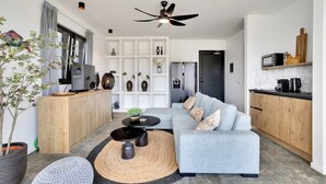 A modern living room with a grey sofa, a black coffee table, and a ceiling fan. - Villa Valena Apartment 1 with Cooling Pool (Kralendijk)