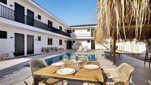 A modern outdoor dining area with a pool, white walls, and a thatched roof. - Villa Valena Apartment 1 with Cooling Pool (Kralendijk)