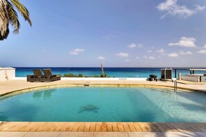A swimming pool with lounge chairs and a view of the ocean. - Belmar Oceanfront Apartment 1, sea views (Kralendijk)