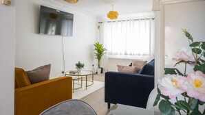 A living room with a sofa, armchair, and a small round table with a plant. - Luxurious 2-bed House in Dartford (Dartford)