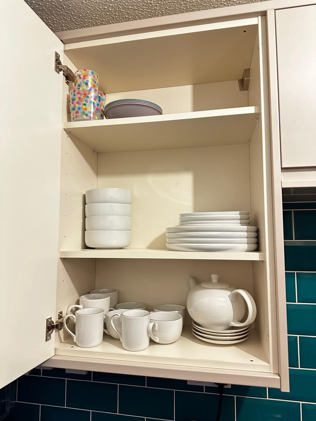 Un armario de cocina con vajilla y tazas blancas.