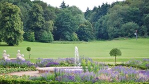A well-maintained garden with a fountain, manicured lawns, and a variety of flowering plants. - 2 Bed 2 Bath Apt Close to Reigate Station - 2230 (Reigate)