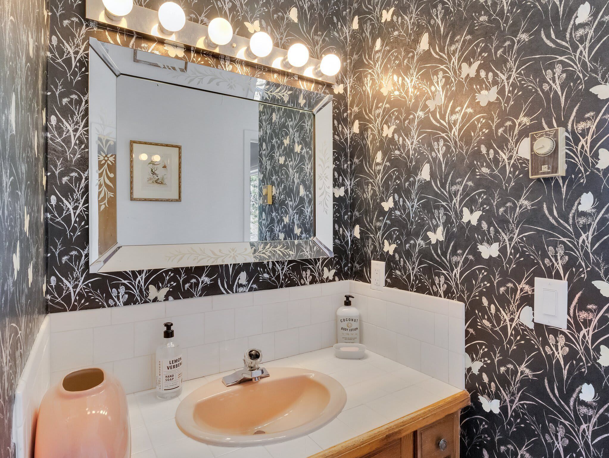 Een badkamer met een wastafel, spiegel en wandlampen.