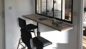 Une chambre moderne équipée d’un bureau, de deux chaises noires, d’un grand miroir et d’une fenêtre.