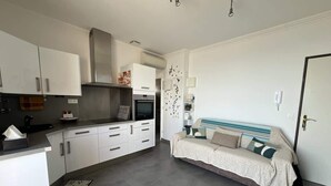Een moderne keuken met witte kasten, een ingebouwde oven en een zithoek met een bank.