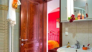 Une salle de bain avec une porte en bois, un lavabo blanc et un miroir au-dessus.