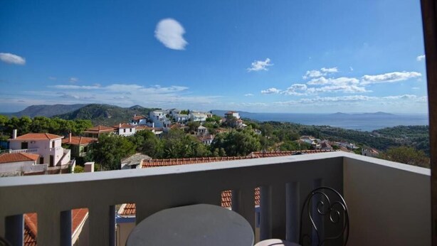 Un balcon avec vue sur un village perché sur une colline et sur la mer.