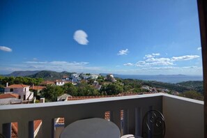 Un balcon avec vue sur un village perché sur une colline et sur la mer.