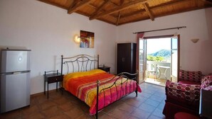 Une chambre avec un lit, une armoire, un bureau, un réfrigérateur et un balcon avec vue.