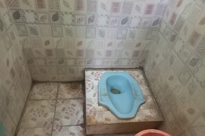 A small bathroom with a blue toilet, patterned tiles, and a tiled floor. - Hotel O Kost Zalfa Amalia Syariah (Adiwerna)
