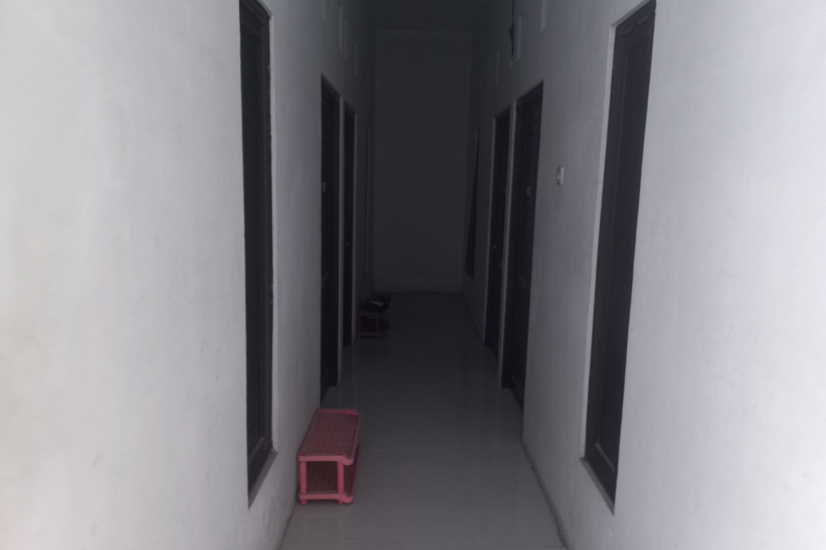 A narrow hallway with doors on both sides and a small red bench in the center.