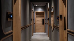 Un pasillo moderno de hotel con puertas de madera, suelo de madera y pared de color claro.