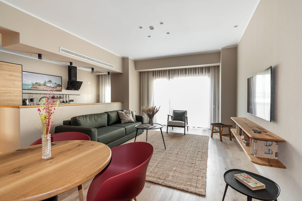 Un salon moderne avec un canapé, une table à manger et un téléviseur fixé au mur.