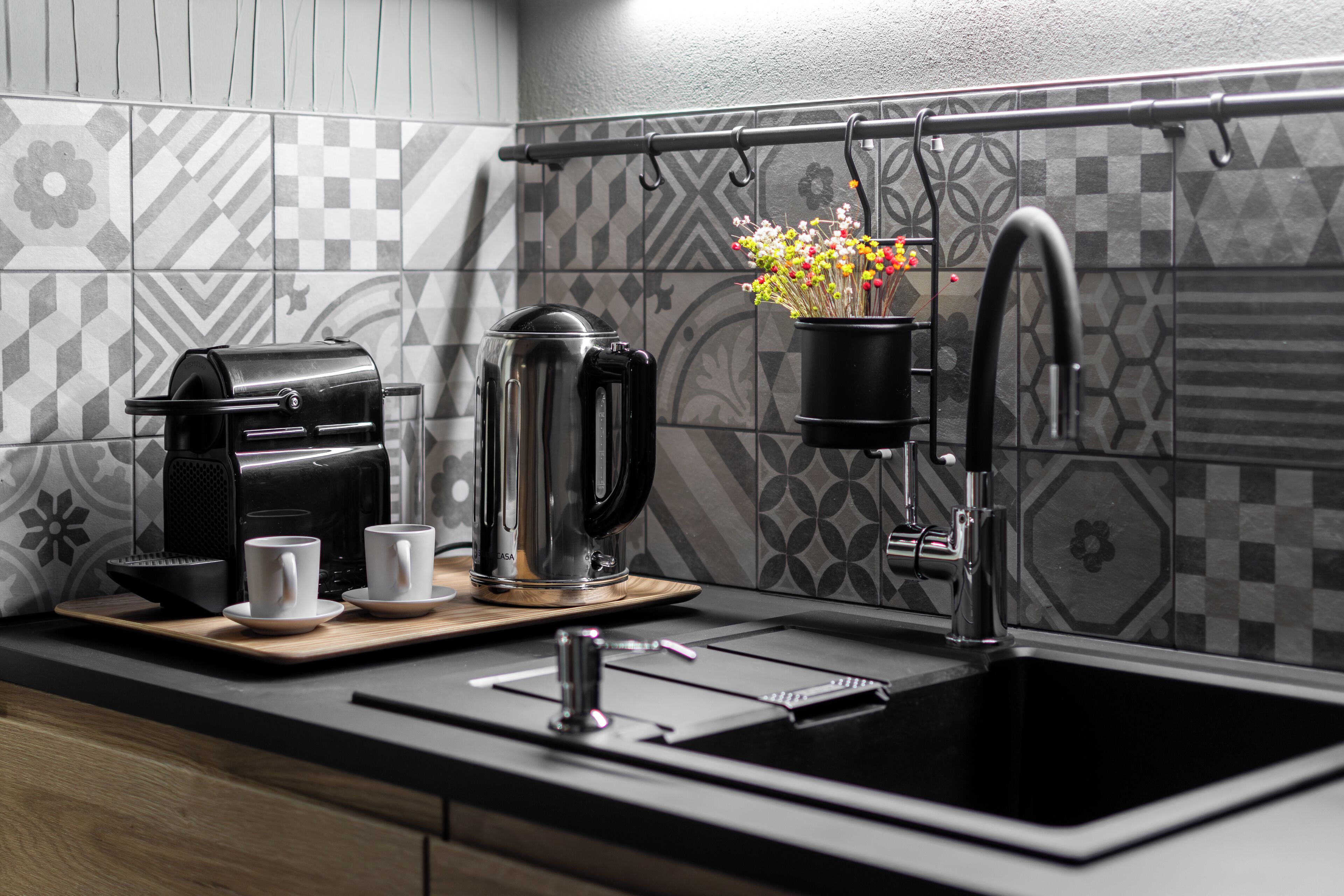 A modern kitchen with a coffee maker, a kettle, and a hanging plant.