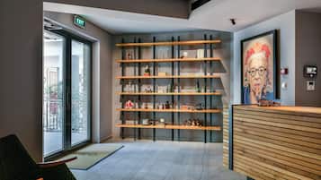 A reception area with a wooden reception desk, a glass door entrance, and a wall-mounted shelf with various items.