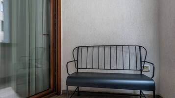 A metal bench with a wooden frame against a textured wall.