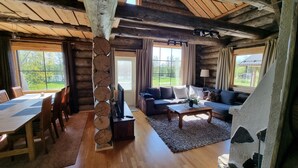 A log cabin interior with a dining area, sofa, and large windows. - Kaunisvirta villa for 10 with beautiful views. Pet-Friendly! (Pyhtään kirkonkylä)