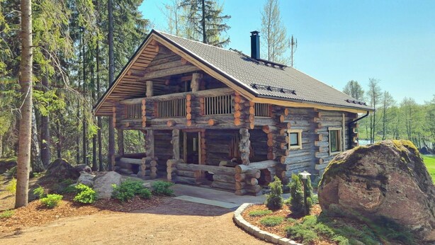A log cabin with a porch, surrounded by trees and a large rock. - Kaunisvirta villa for 10 with beautiful views. Pet-Friendly! (Pyhtään kirkonkylä)
