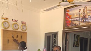 A reception area with a wooden counter, clocks displaying different time zones, and a sign for 'JIK'. - JLK Guest House & Events Centre (Koforidua)
