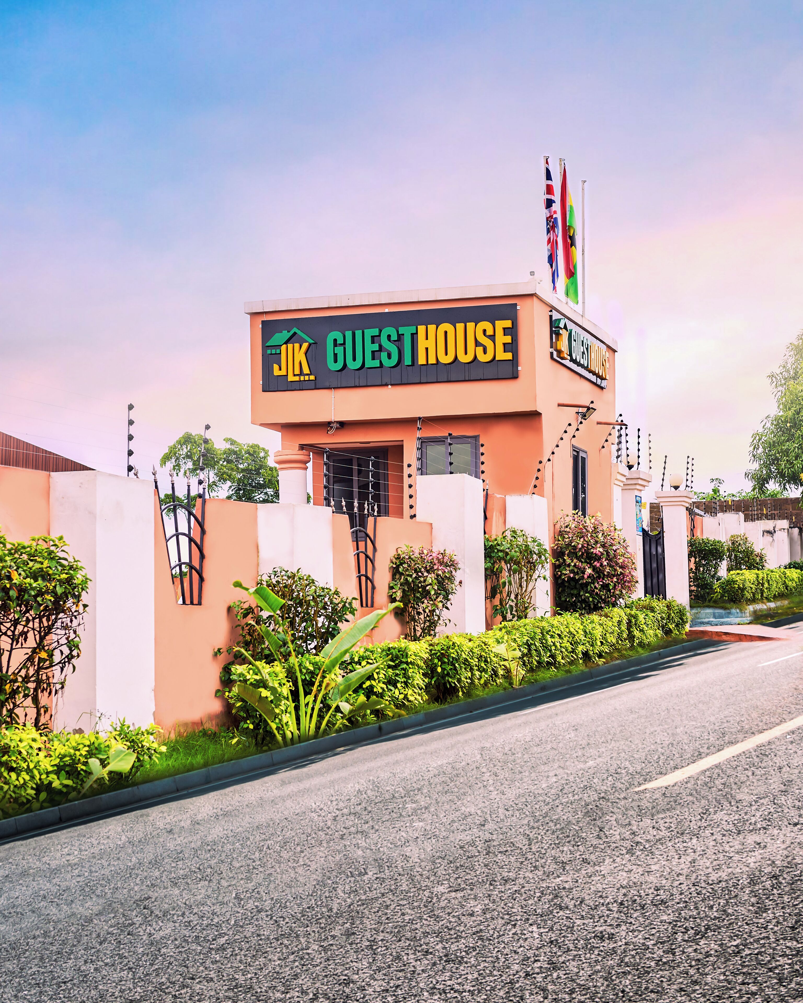 A building with a sign reading "GUEST HOUSE" and multiple flags.