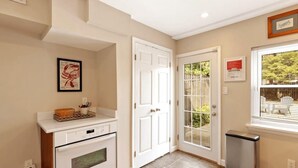 A kitchen with a white oven, a white countertop, and a trash can. - Fells Point Fenced in Yard Weber Gas Grill (Baltimore)