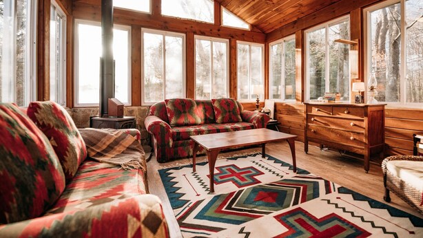 Une pièce chaleureuse avec un plafond en bois, de grandes fenêtres, un canapé, une table basse et une commode.