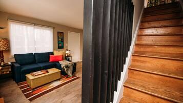 Ein Wohnzimmer mit einer Couch, einem Couchtisch und einer Treppe.