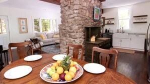 A dining area with a stone fireplace, wooden dining table, and chairs.