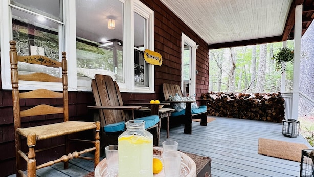 A wooden deck with a rustic bench, a vintage suitcase, and a tray with a beverage and lemon.