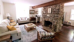 A living room with a stone fireplace, a sofa, a chair, and a coffee table.