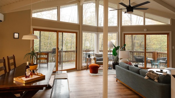 A spacious living area with a large wooden dining table, a sofa, and a balcony with outdoor seating.