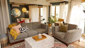 A living room with a grey sofa, a matching armchair, a small coffee table, and a large mirror.
