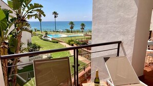 Een balkon met uitzicht op de oceaan, een zwembad en een fles champagne.