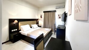 A hotel room with a bed, bedside tables, a desk, a chair, a TV, and artwork on the walls. - Vita Blu Studios (Zakynthos)