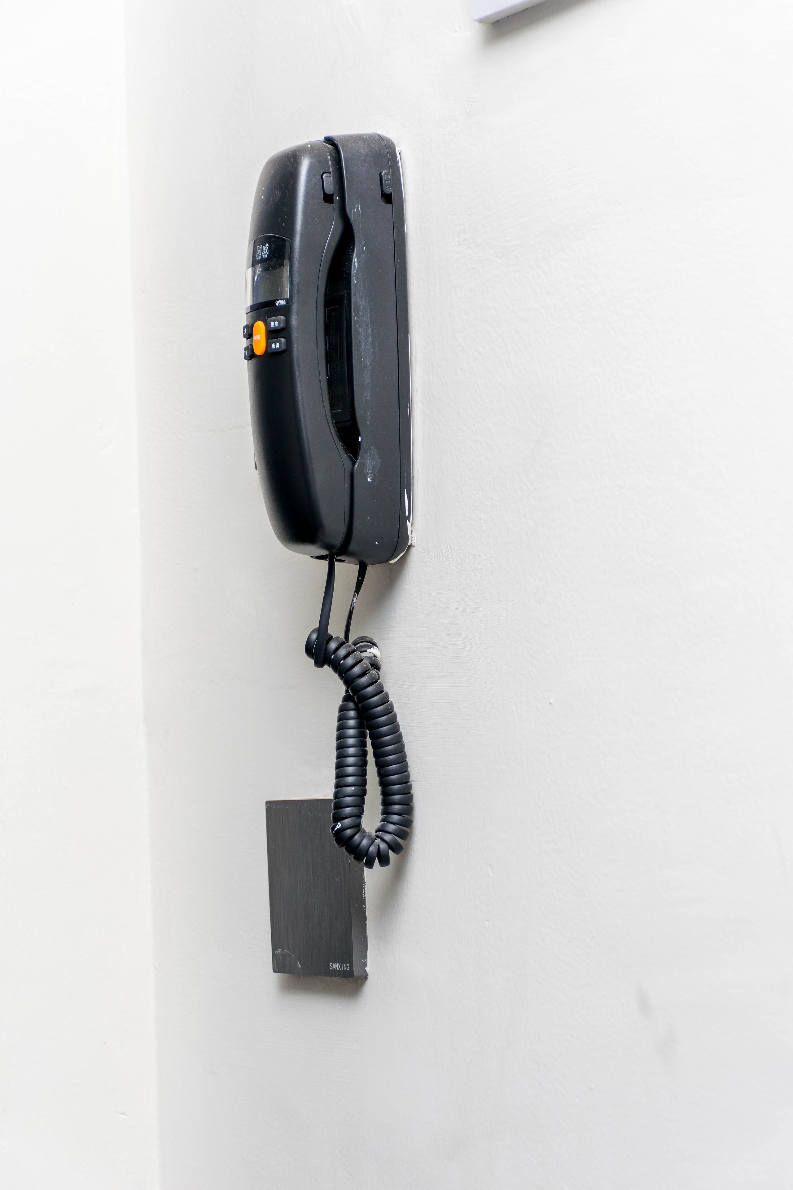 Een zwarte telefoon bevestigd aan een witte muur.