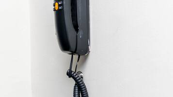 Een zwarte telefoon bevestigd aan een witte muur.