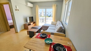 Una sala de estar moderna con una mesa de comedor de madera, un sofá y un televisor.
