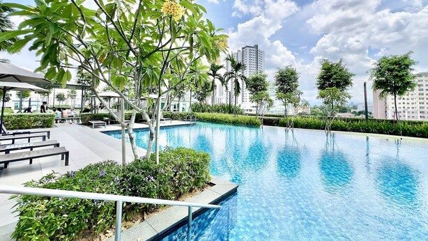 A swimming pool surrounded by greenery and benches, with a clear sky and buildings in the background. - Plaza Kelana Jaya by Sleepy Bear (Petaling Jaya)