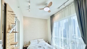 A modern bedroom with a bed, a ceiling fan, a window with curtains, and a wall-mounted drying rack. - Plaza Kelana Jaya by Sleepy Bear (Petaling Jaya)