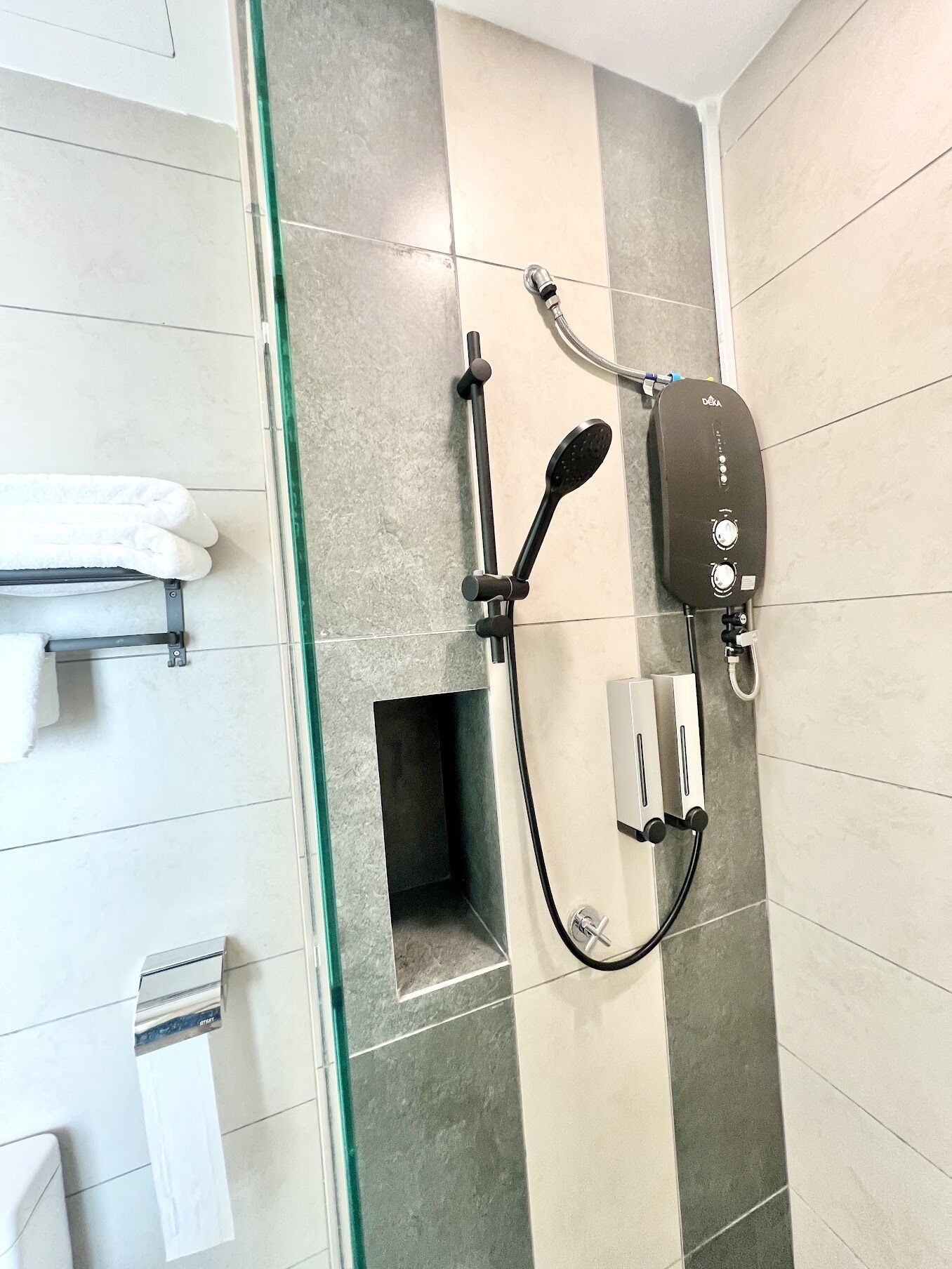 A shower with a handheld showerhead, a wall-mounted control panel, and a glass-enclosed shower stall.