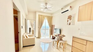 A modern living room with a sofa, a dining table with chairs, a TV, and a balcony with a view. - Plaza Kelana Jaya by Sleepy Bear (Petaling Jaya)